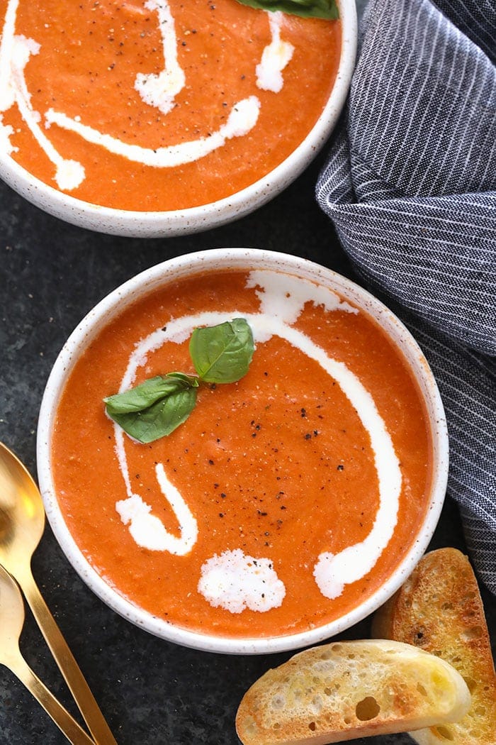 This flavorful Tomato Bisque Soup is made in under 20 minutes. Made with Greek yogurt and fresh basil, you'll get all the flavor with a healthy twist! tomato bisque in bowls