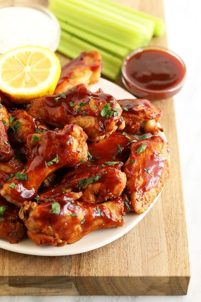 Love chicken wings, but don't want to heat up your whole house? Make our amazing Crockpot Chicken Wings for your next appetizer or snack. Bonus, these crockpot bbq chicken wings aren't fried, so they're on the healthier side! plate of chicken wings with bbq sauce