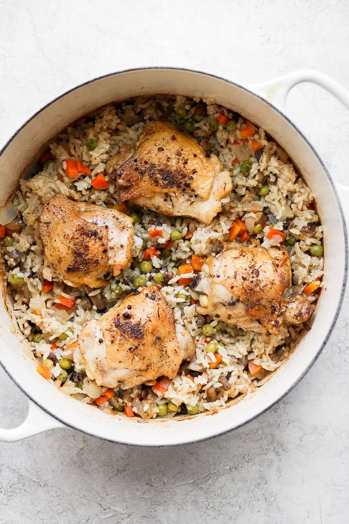 The most flavorful chicken and rice recipe on the internet. Our chicken and rice bake is made with juicy chicken thighs and a delightful rice medley so you get extra veggies! chicken and rice in Dutch oven.