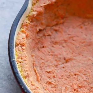 Close-up of a sweet potato crust quiche in a red baking dish with a partially visible black rim.