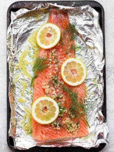 salmon on top of foil with dill and lemons.