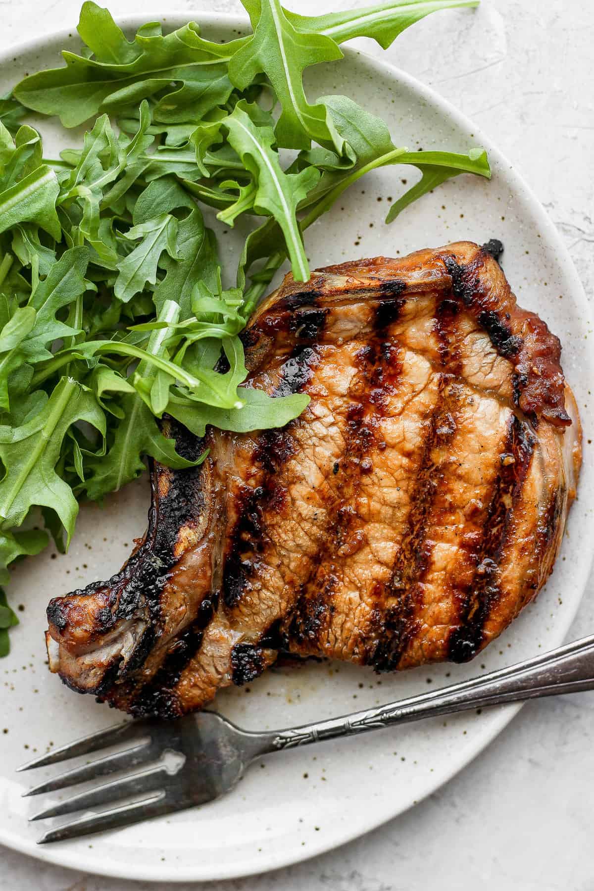 This sweet and salty pork chop marinade is our go to when flavoring pork chops. It's made with 5 simple ingredients and is so juicy! pork chop on plate.