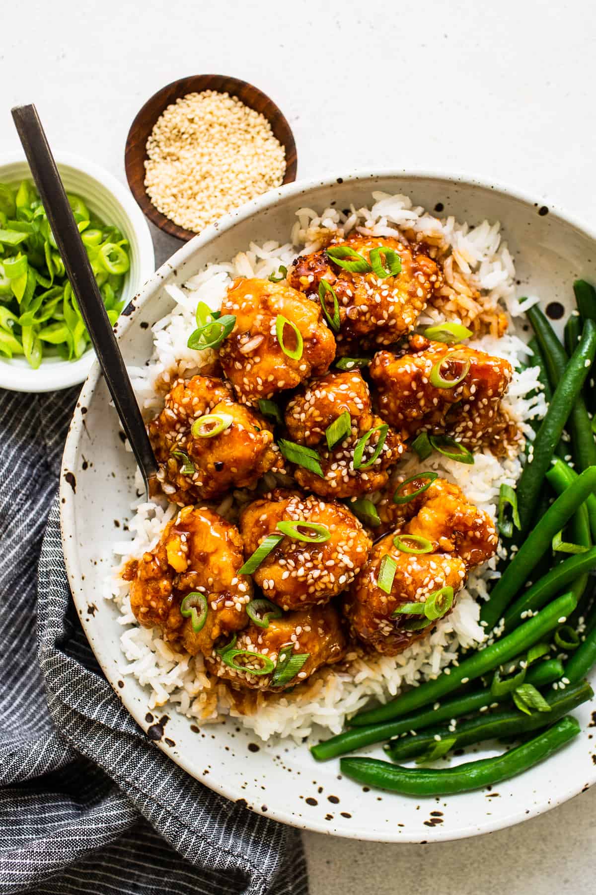 This saucy, delicious air fryer honey sesame chicken is ready in 30 minutes and tastes deep-fried, but it's actually made in the air fryer! sesame chicken in bowl with veggies