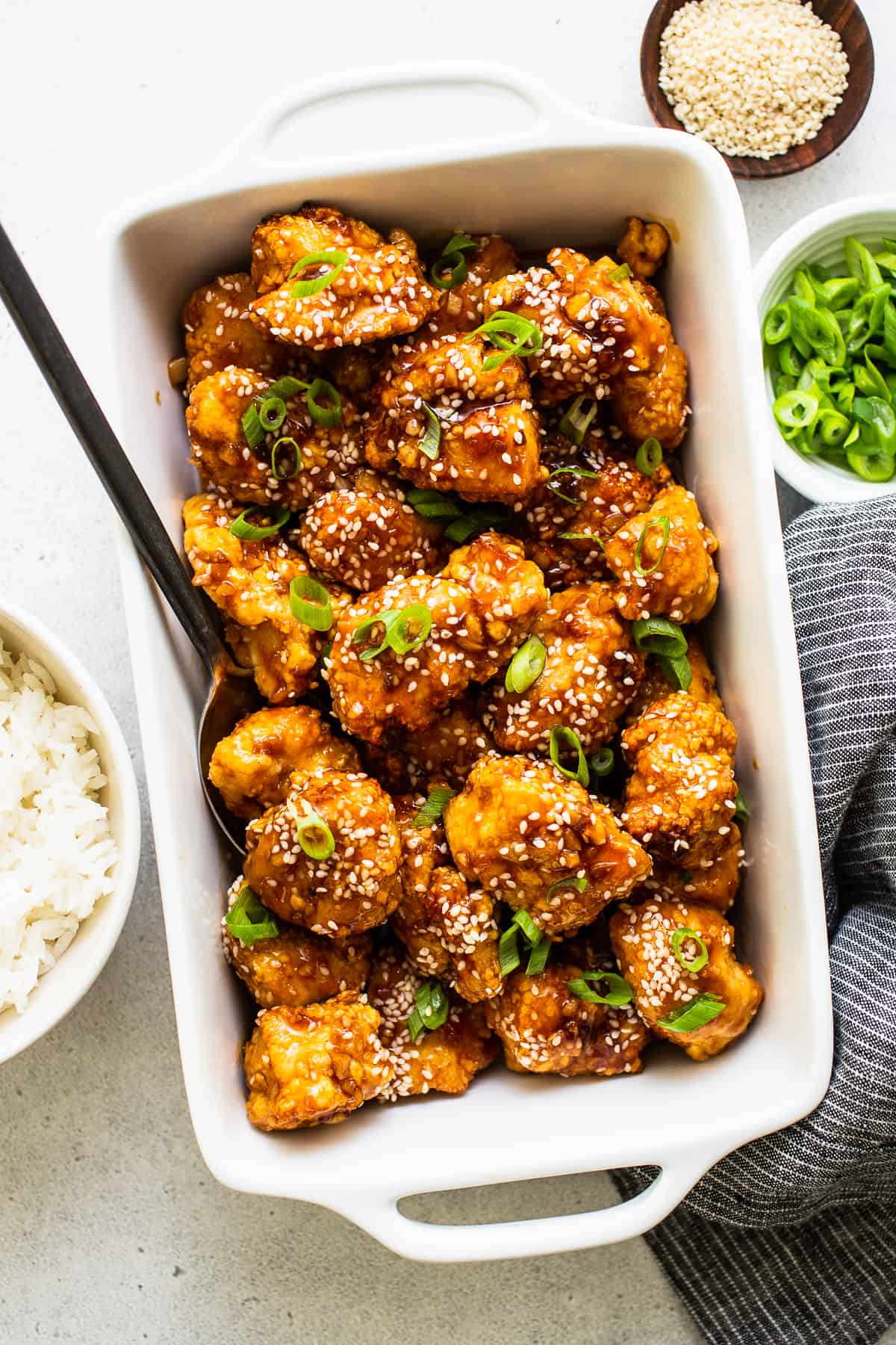 This saucy, delicious air fryer honey sesame chicken is ready in 30 minutes and tastes deep-fried, but it's actually made in the air fryer! honey sesame chicken in dish with sesame seeds