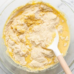 A bowl of batter with a wooden spoon in it.