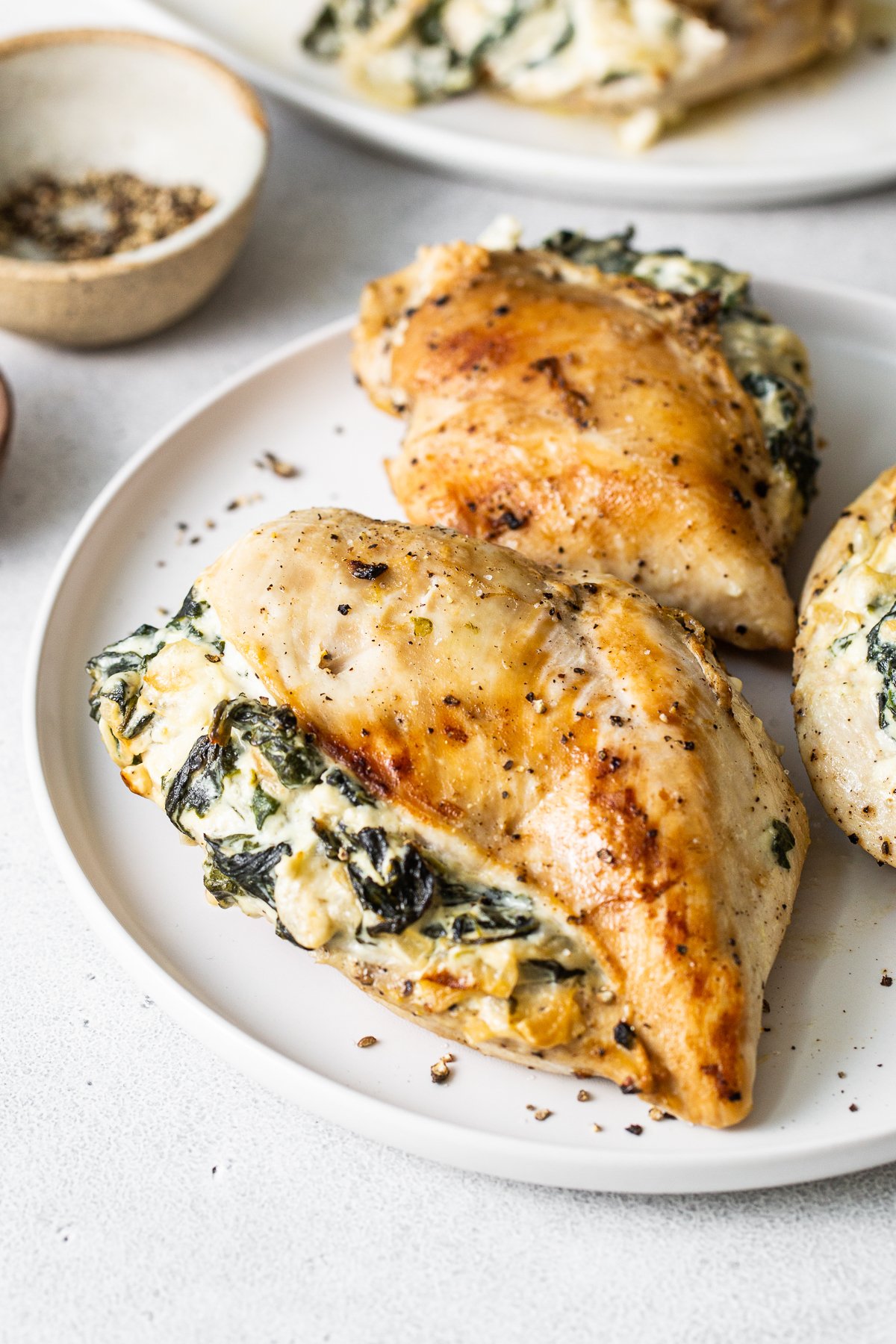 This spinach stuffed chicken breast will be one of your new favorite recipes — and for good reason! No one can resist juicy chicken breasts stuffed with an oozy, cheesy spinach filling. Spinach stuffed chicken breast on a plate.