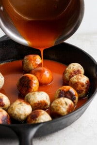 adding sauce to meatballs.