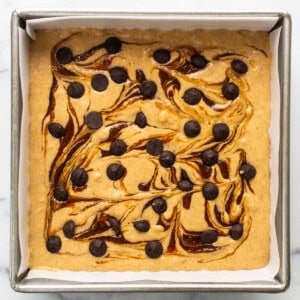 A brownie with chocolate chips and caramel sauce in a baking pan.