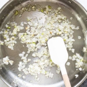 Sauteing onions in a pan with a wooden spatula.