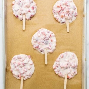 Strawberry popsicles on a baking sheet.