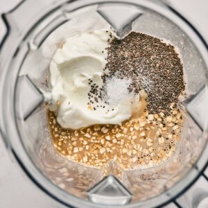 Ingredients in a blender: yogurt, chia seeds, salt, oats, and a liquid.